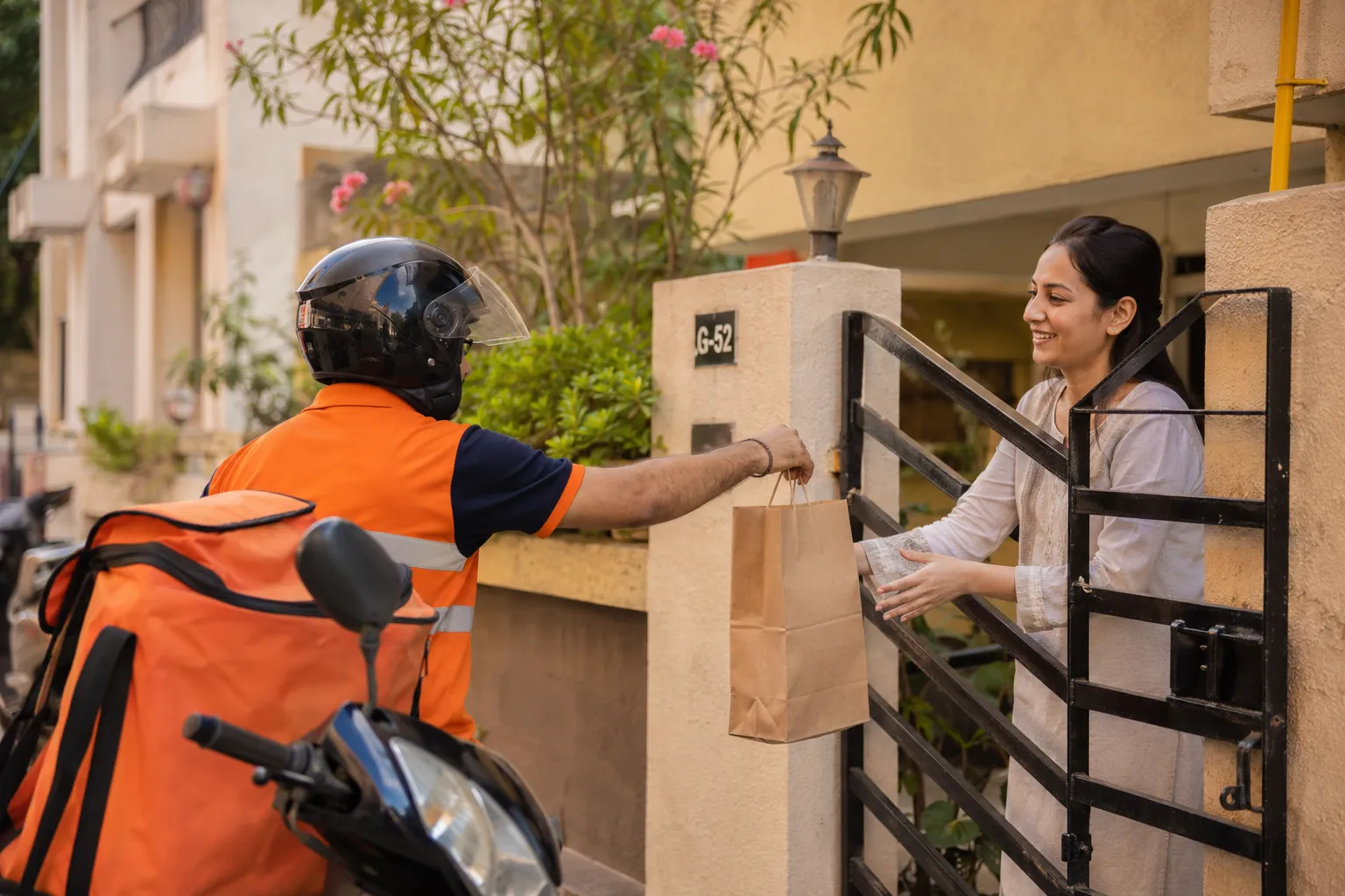 Swiggy Instamart delivery rider handing over an order at a residential gate