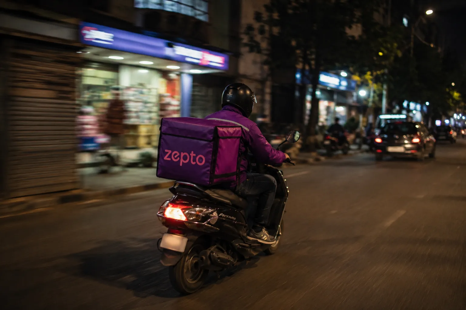 Zepto delivery rider on a scooter at night